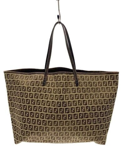 FENDI canvas tote bag with all-over FF logo pattern and brown leather handles, hanging against a white background.