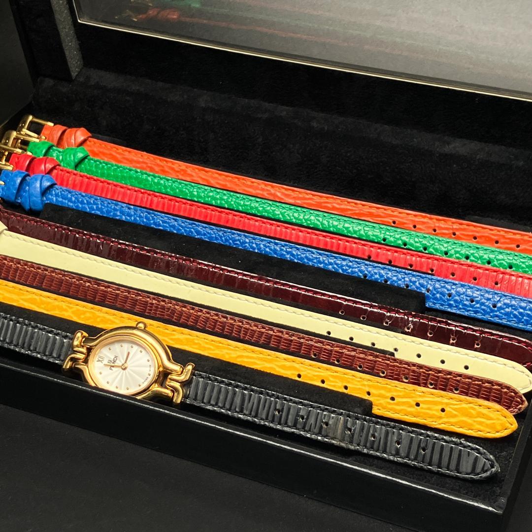 Multiple colorful cow leather interchangeable watch straps and a gold-toned watch head arranged in a black presentation box.