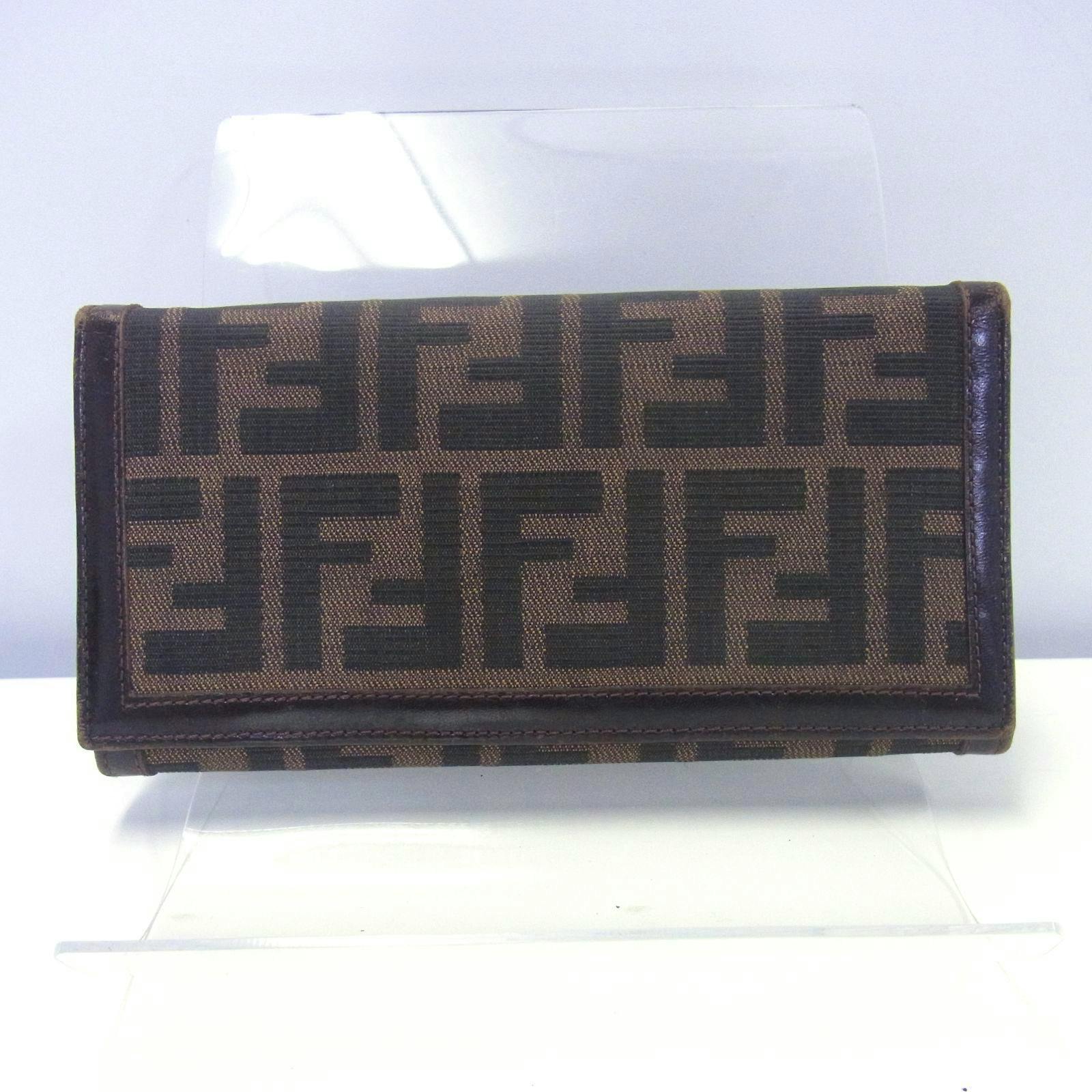 Front view of a FENDI brown Zucca-pattern long canvas wallet displayed on a clear stand.