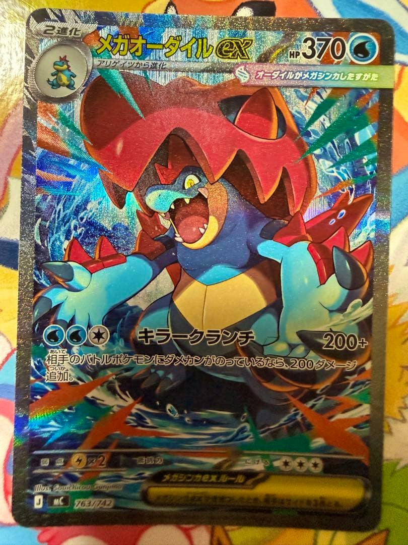 Photo of the holographic Japanese trading card メガオーダイルex showing the card face with artwork, HP 370, and Japanese text.