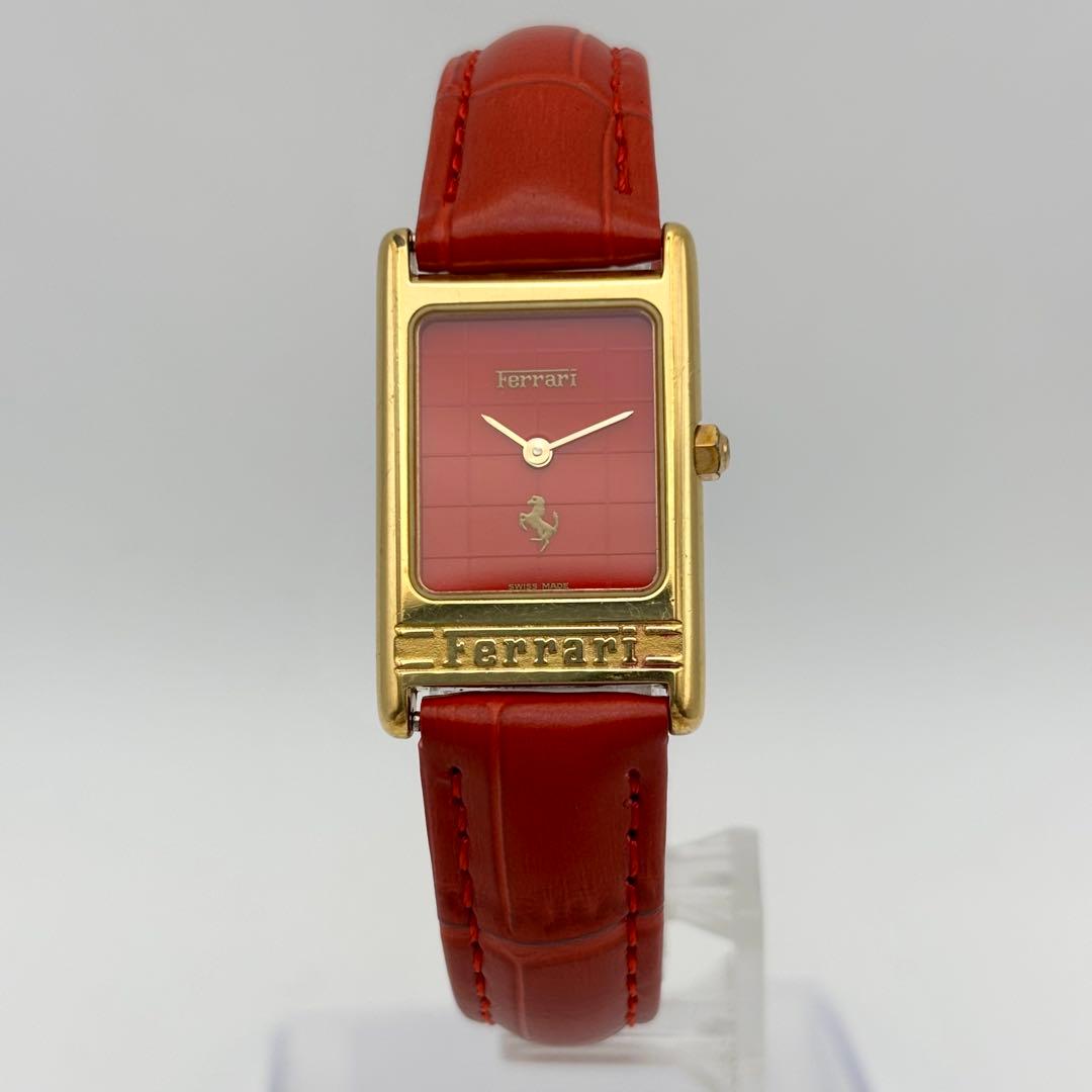 Gold-tone rectangular Ferrari Cartier wristwatch with a red dial and red leather strap on a white background.