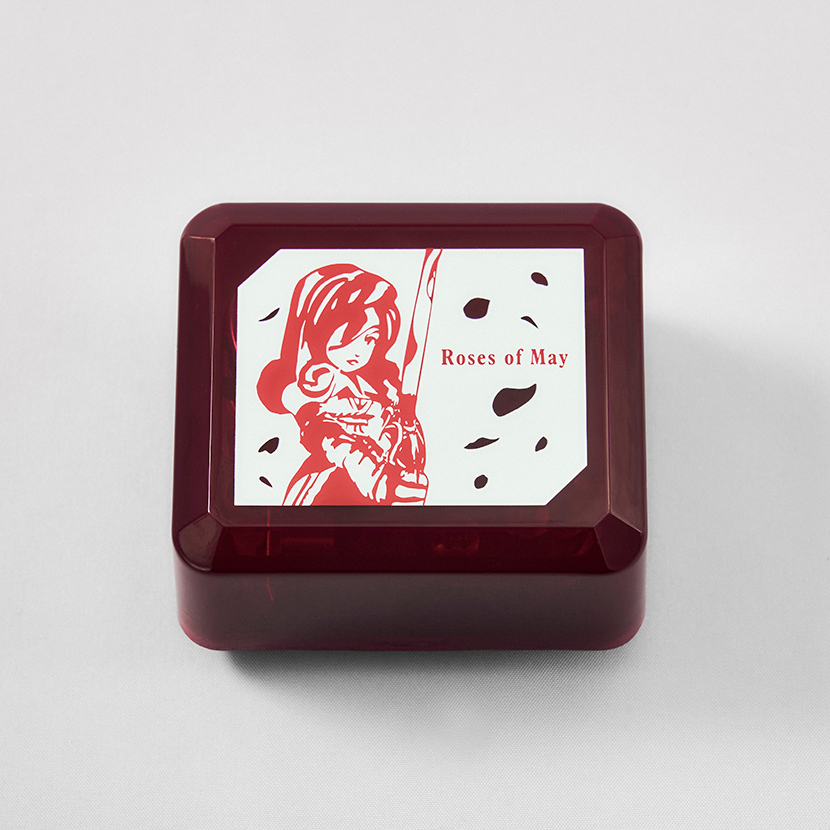 Red rectangular music box with an illustrated lid featuring a character and the text 'Roses of May'.
