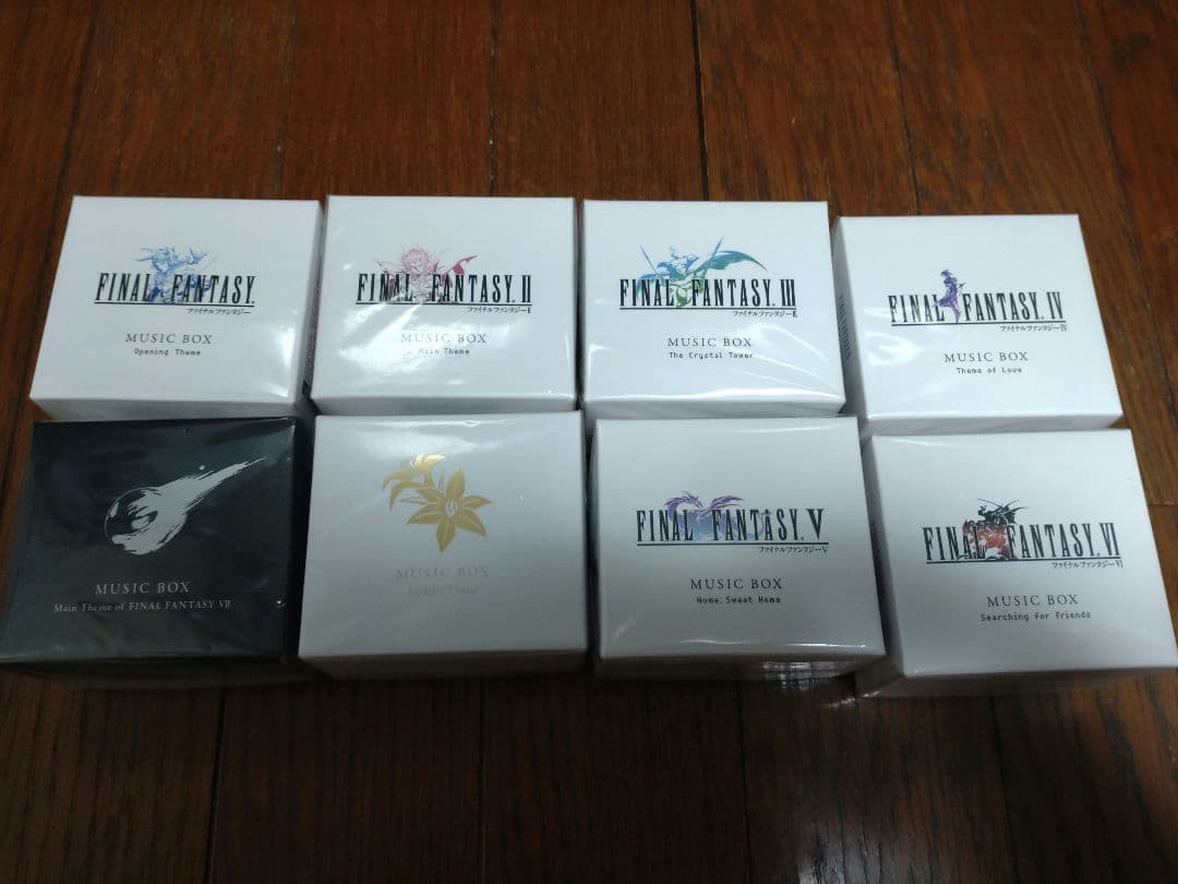 Eight boxed Final Fantasy music boxes arranged in two rows on a wooden floor.