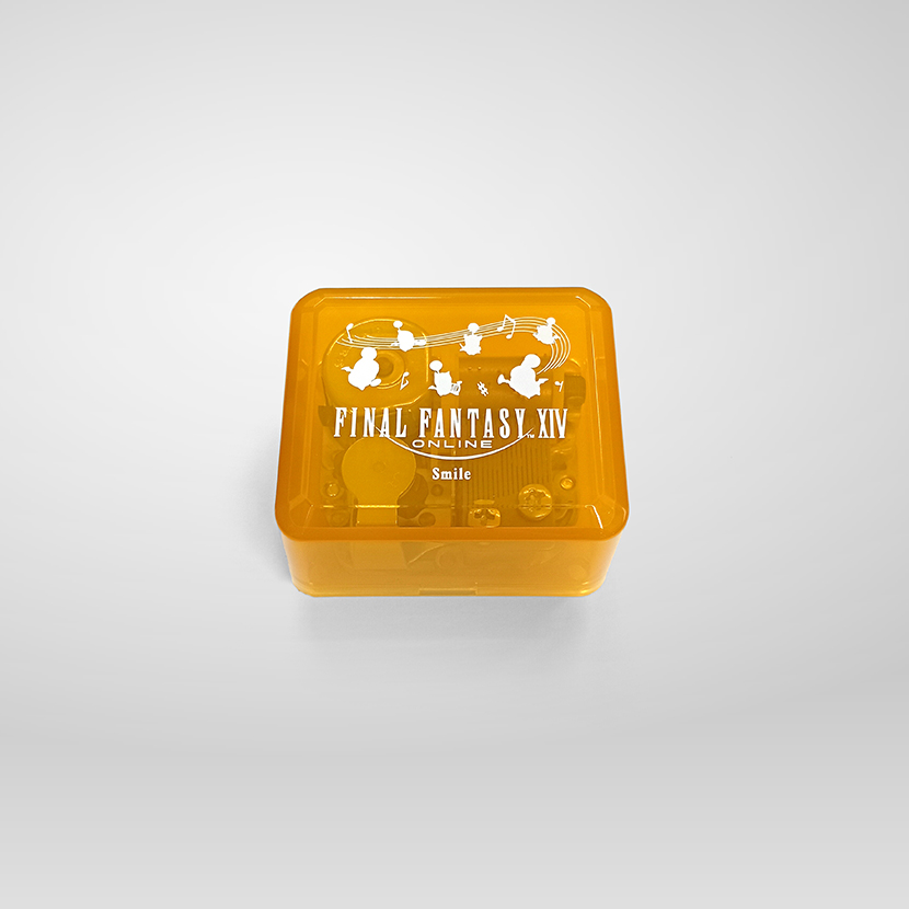 A square translucent orange music box with white FINAL FANTASY XIV branding and the word "Smile" on the lid.