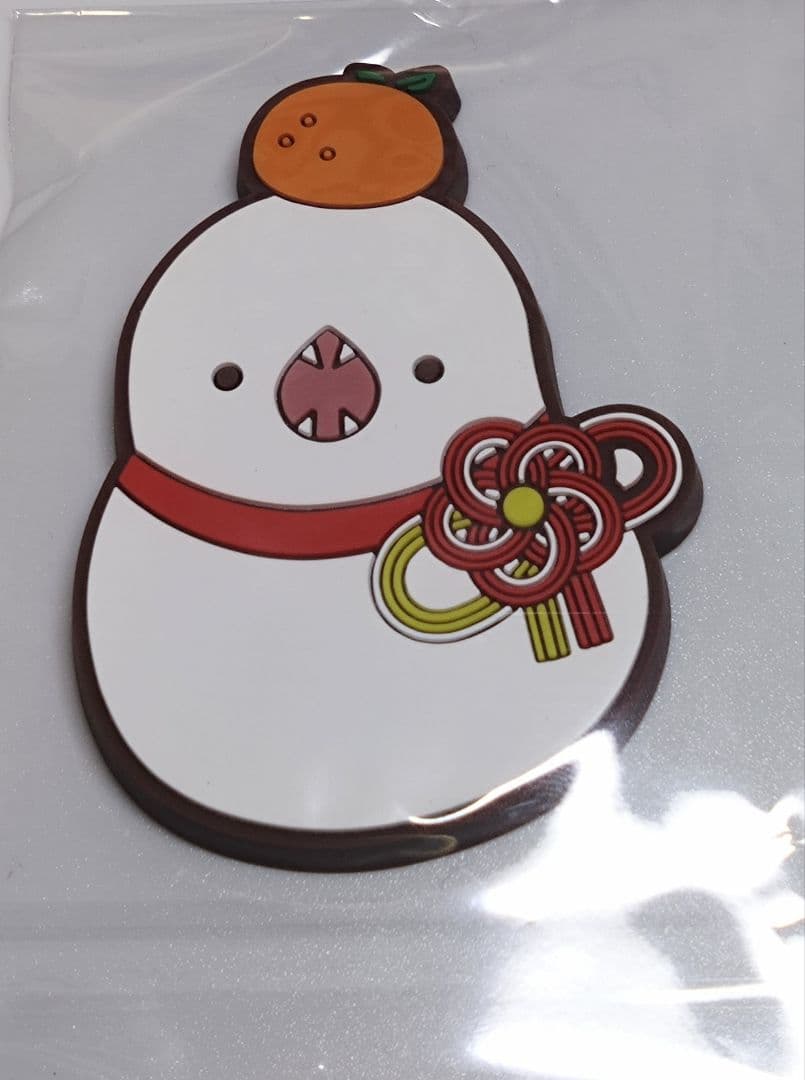 Close-up of the FF14 rubber fridge magnet showing a white Tsuchinoko-like character with an orange on its head and a decorative red knot, in clear plastic packaging.
