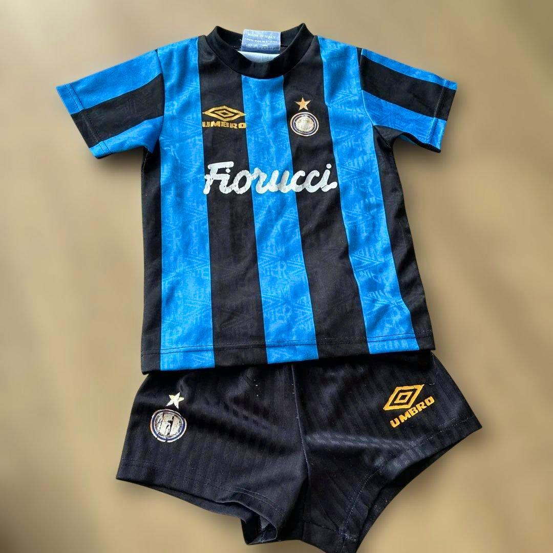 Blue-and-black striped Fiorucci Inter jersey with matching black shorts laid flat on a beige background.