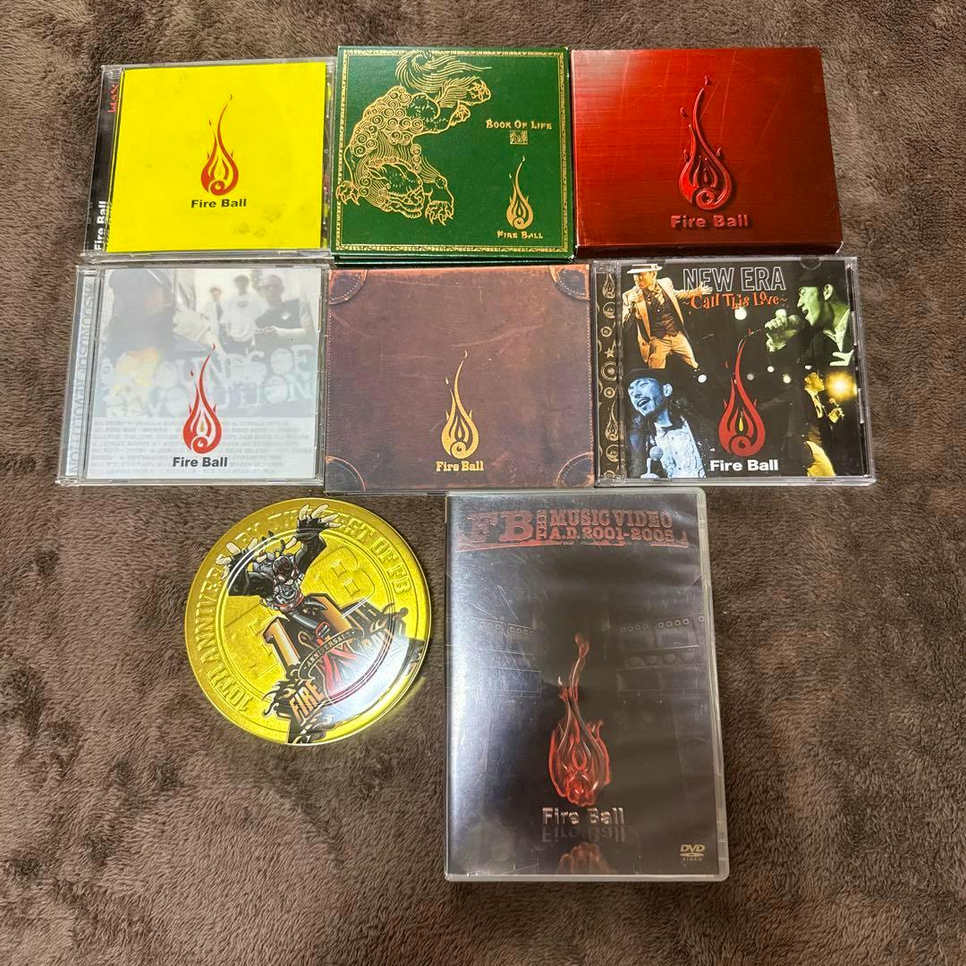 Photo of eight Fire Ball CDs and DVDs arranged on a brown surface.