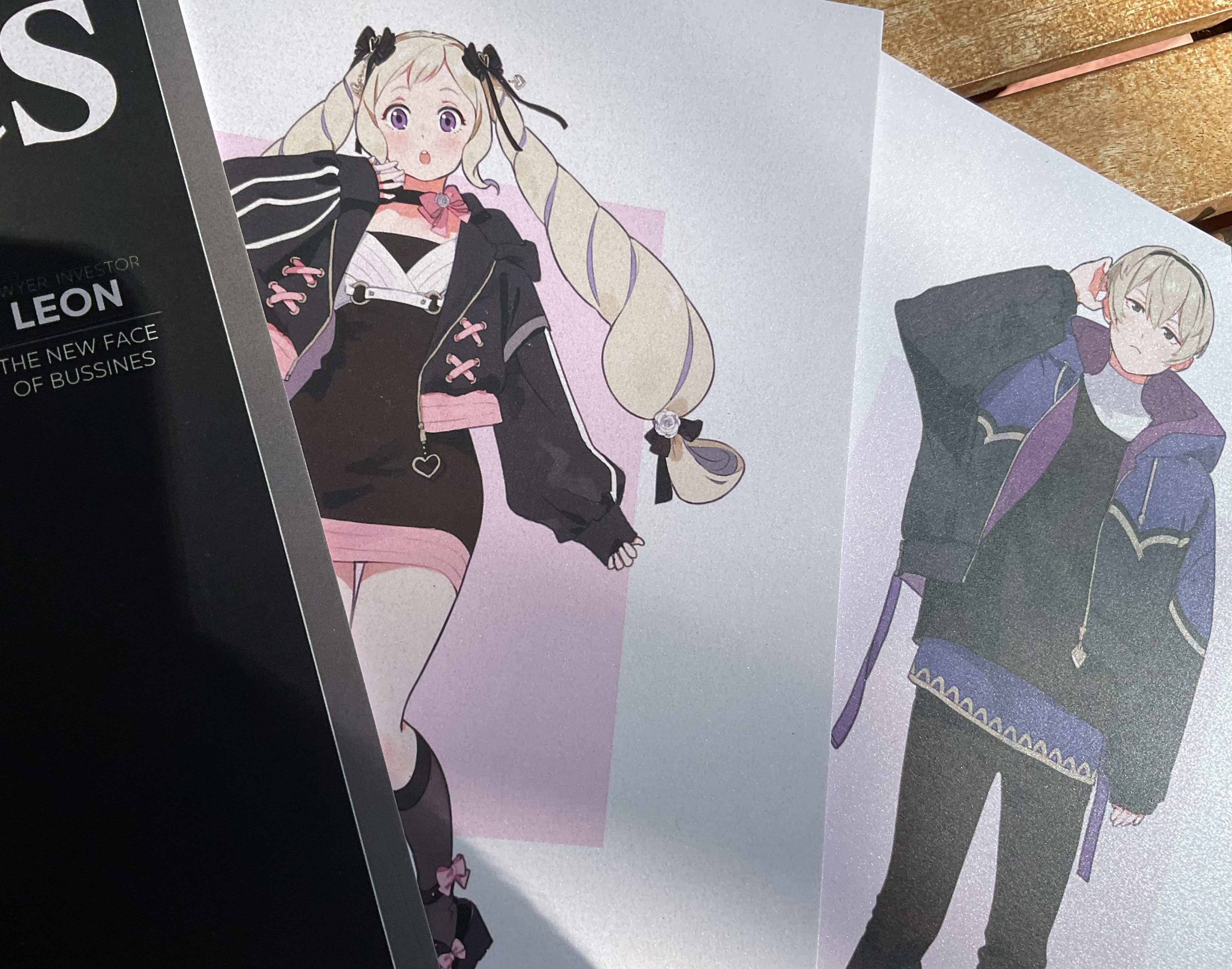 Photograph of A5 postcards showing two illustrated characters printed on glossy paper.