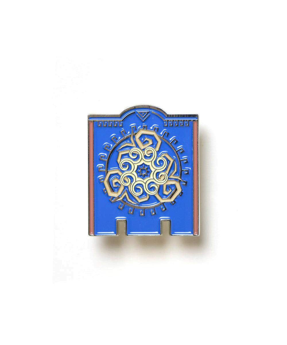Front view of a blue and gold Fire Emblem enamel pin showing an ornate circular emblem.