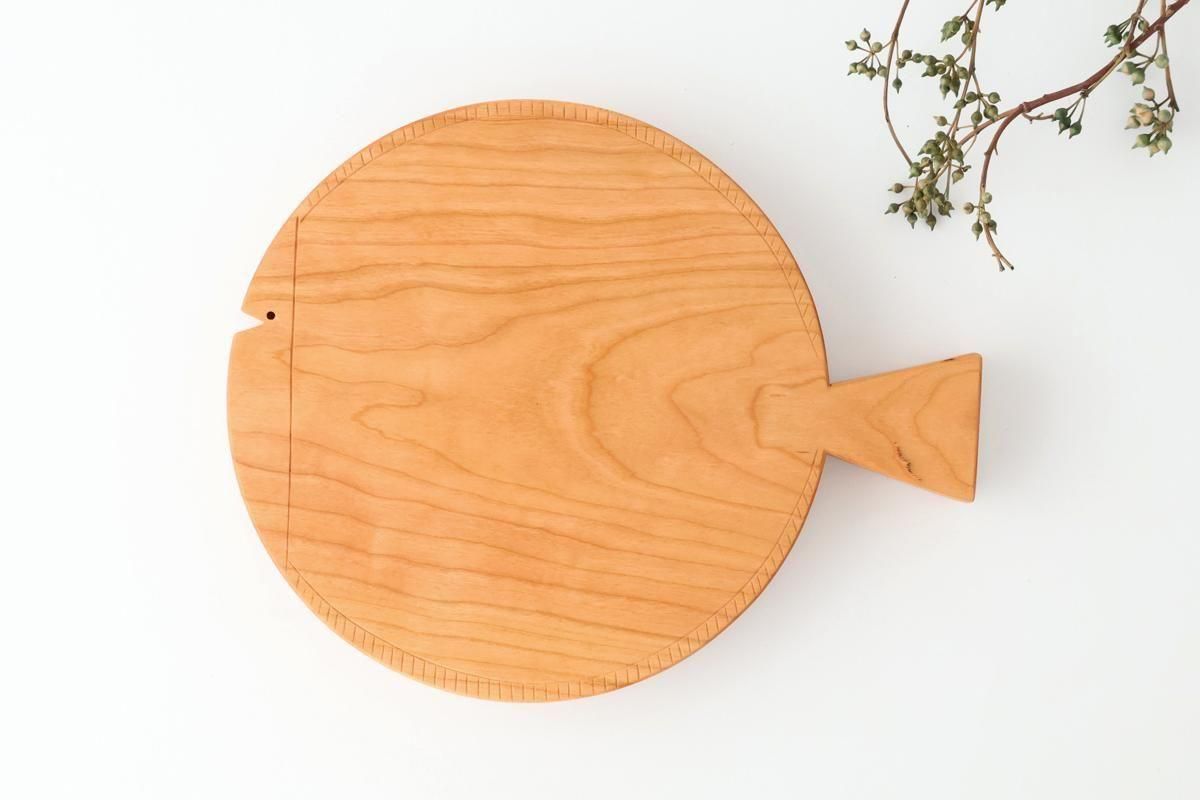 Top-down photo of a cherry wood fish-shaped cutting board (210mm) showing its round body and tail handle.