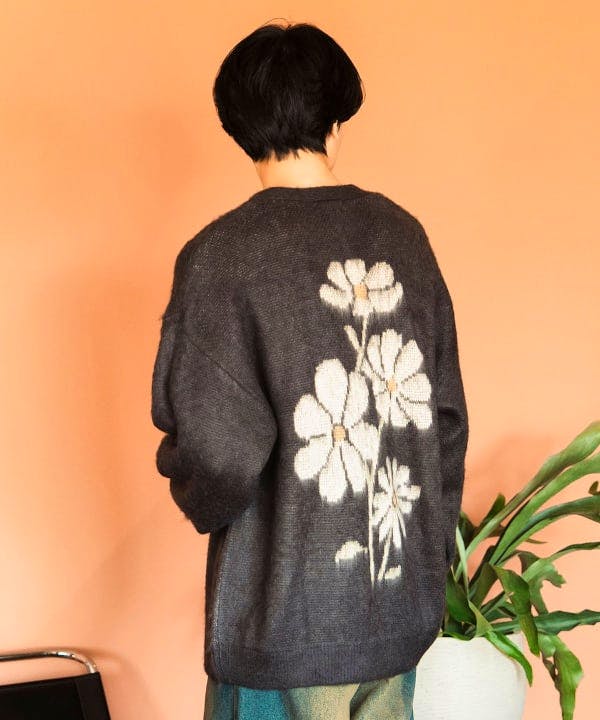 Back view of a person wearing a cardigan featuring large white flower jacquard on the back.