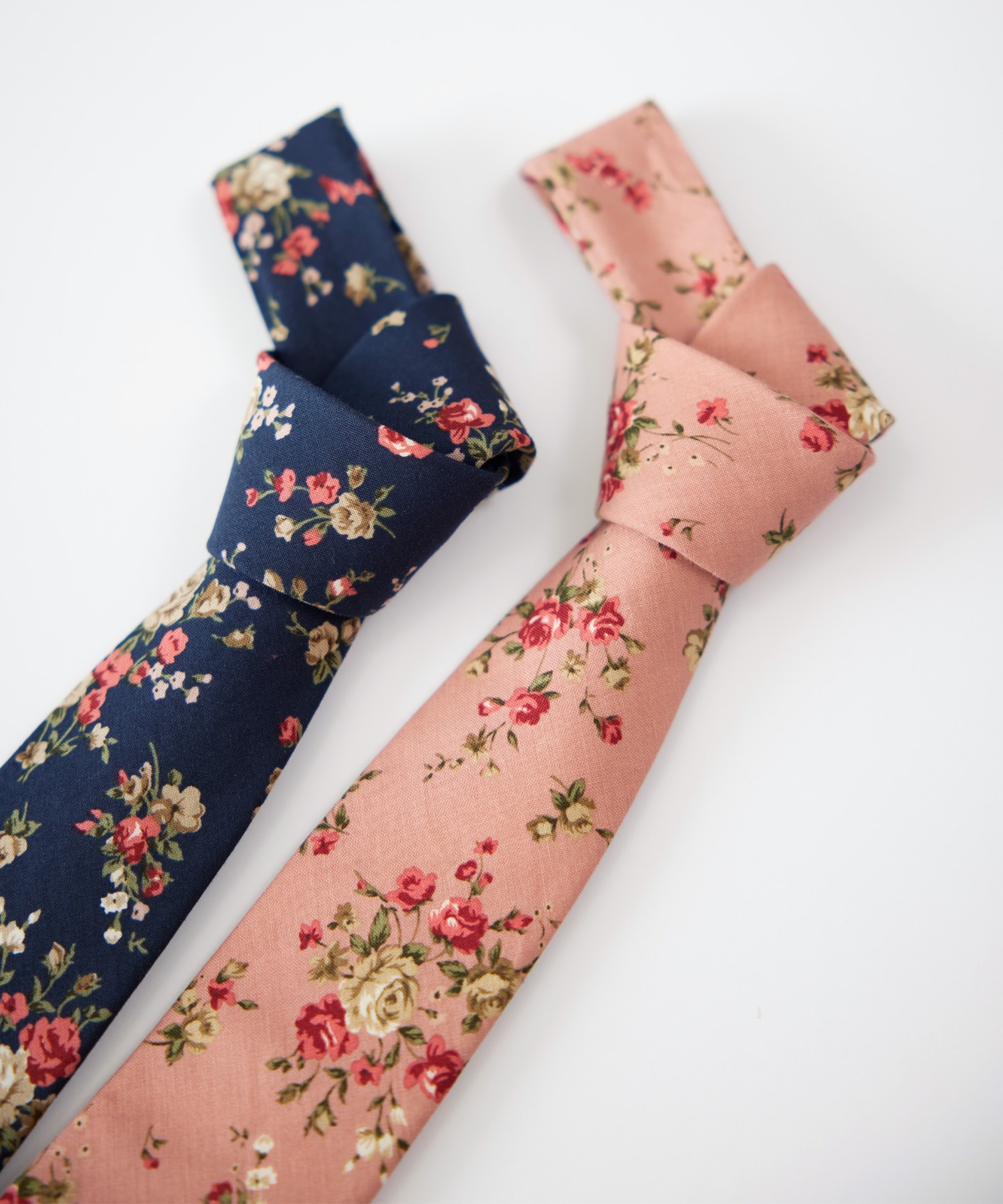 Two floral silk neckties in navy and pink laid flat with knots visible.
