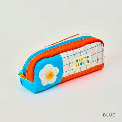 Blue and orange rectangular cotton pouch with a white flower button applique, grid-pattern panel, and top zipper.