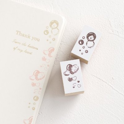 Two rectangular rubber stamps with wooden bases showing bubble and heart motifs placed beside a notebook with similar stamped designs.
