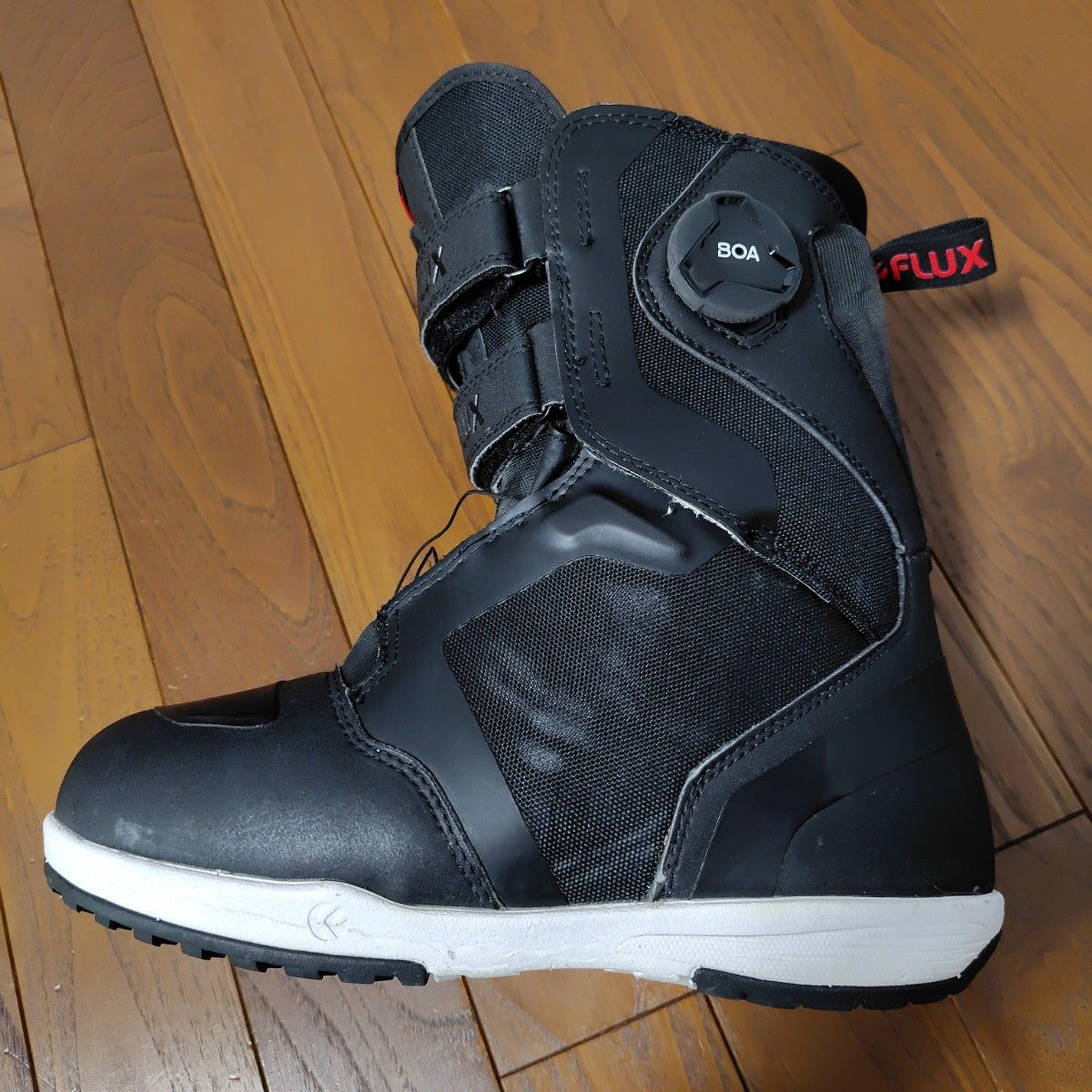 Left outer of a FLUX 24 model HB-BOA snowboard boot (26 cm) in black placed on a wooden floor.