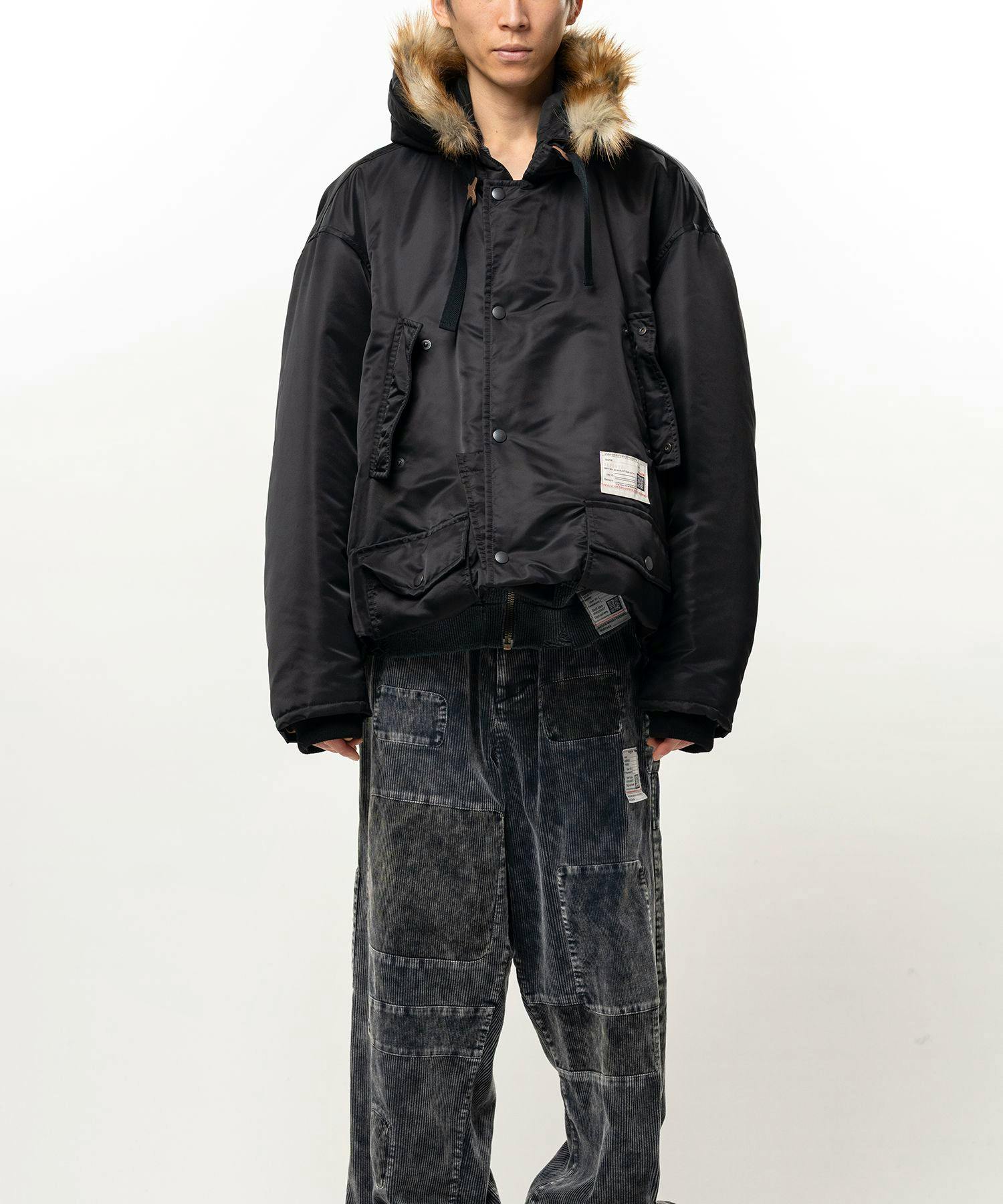 Front view of the men's Folded Hem Mountain Hooded Jacket worn by a model, showing the hood with fur trim and front pockets.