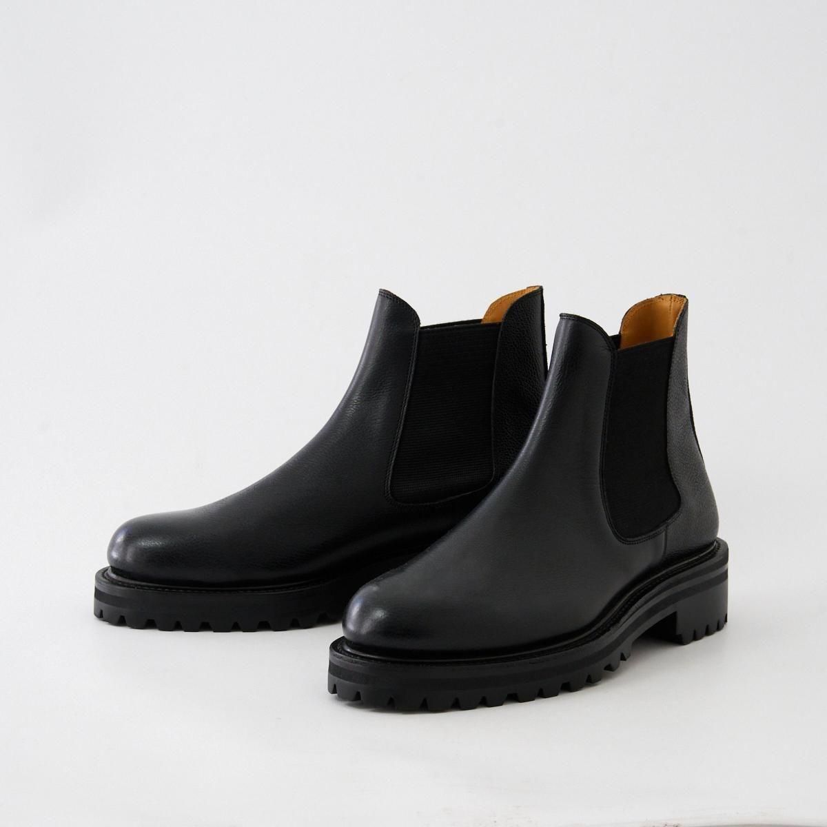 Pair of black men's side gore grain leather boots on a white background.