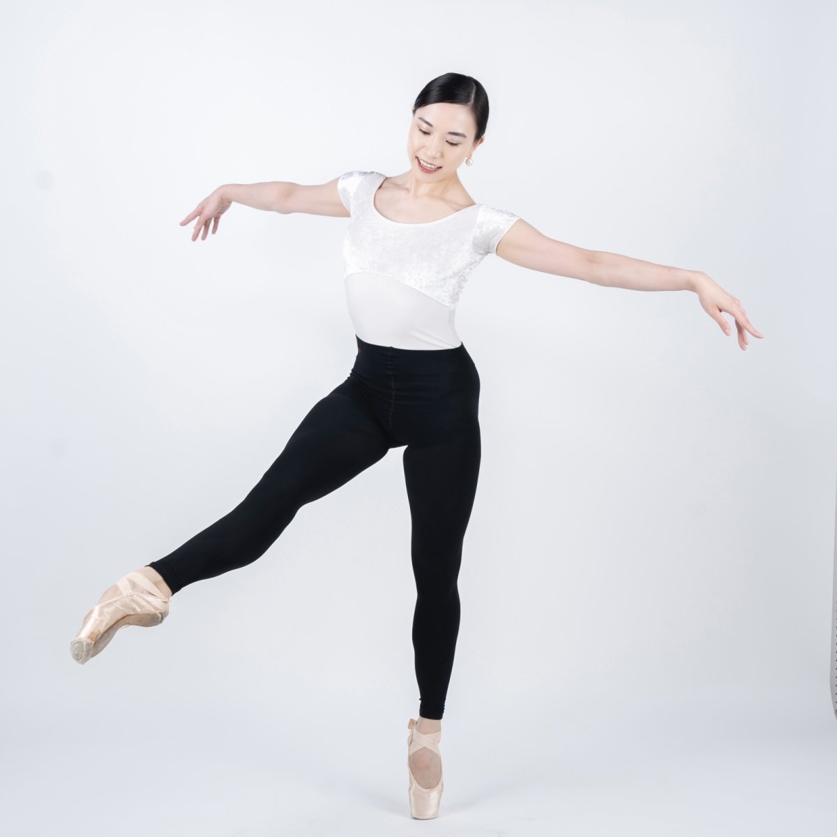Model wearing black women's taping leggings in a studio while posing en pointe.