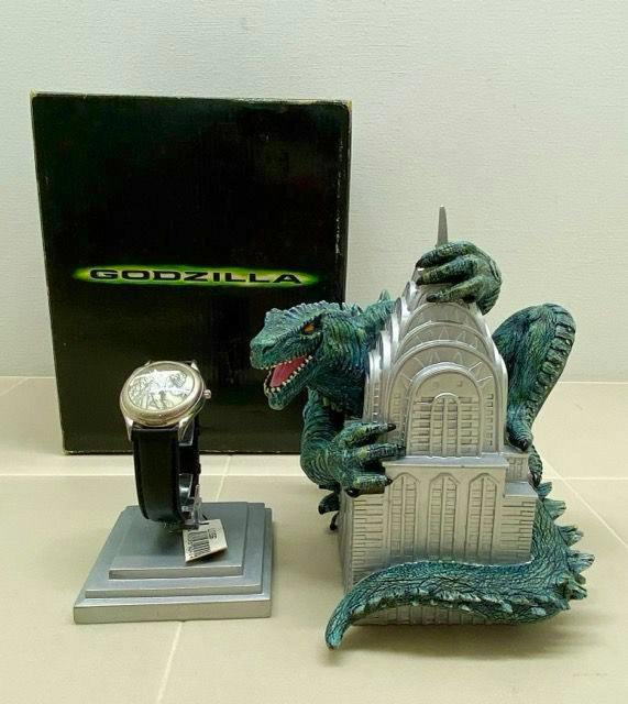 Fossil Godzilla wristwatch on a display stand beside a Godzilla decorative stand and the branded product box.