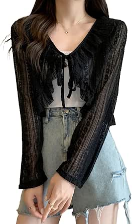 Model wearing a black sheer open-front short cardigan with long sleeves over a white top and denim shorts.
