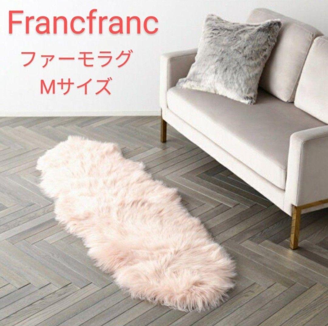 Pink fur rug placed on a wood floor next to a light-colored sofa.