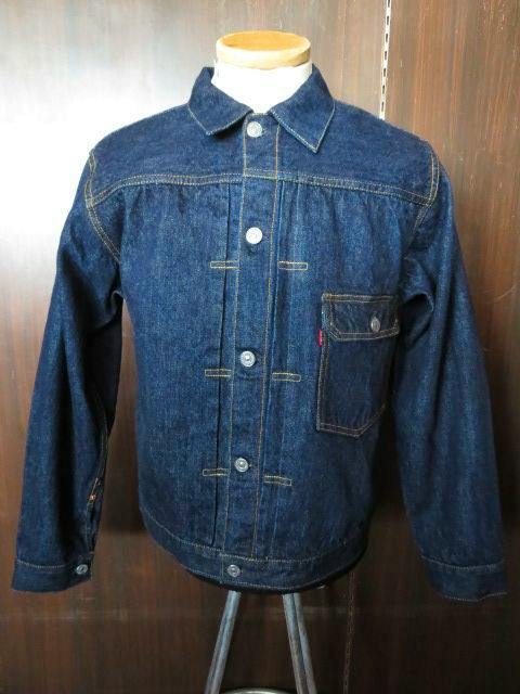 Front view of the men's indigo denim jacket on a mannequin showing button-front closure, left chest pocket, and contrast stitching.