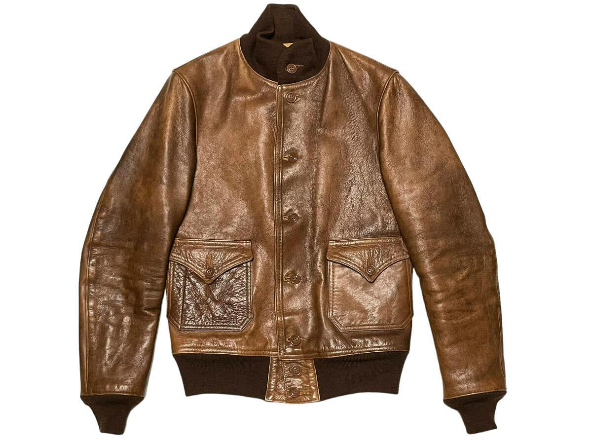 Brown horse leather Type A-1 men's jacket laid flat showing the front, flap pockets, buttons, and ribbed cuffs.