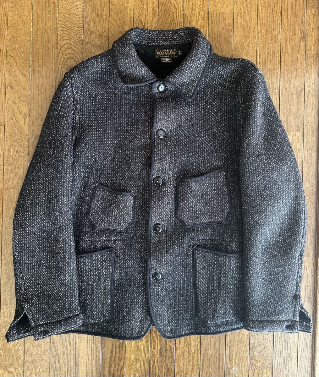 Front-view flat-lay of the men's wool Freewheelers Winter Worker “Longshoreman” jacket on a wooden floor, showing button closure and four patch pockets.