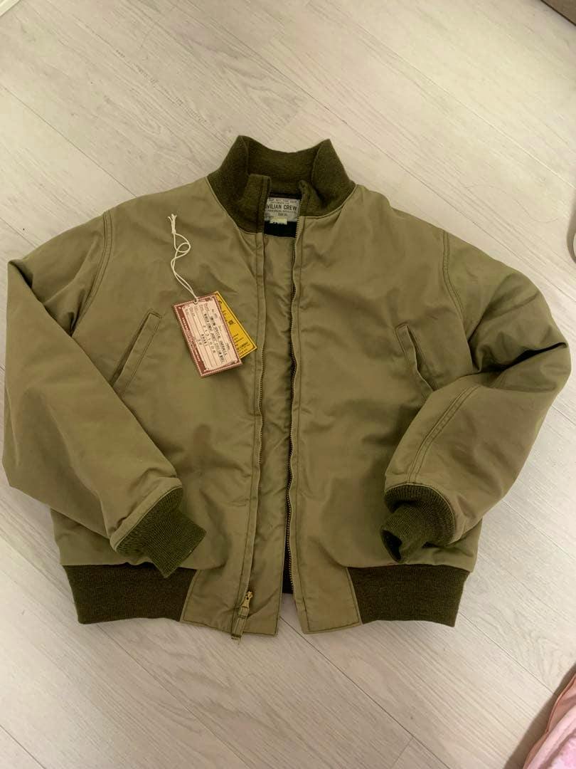 Men's cotton tankers jacket (size 38) laid flat on a light floor with tags attached.