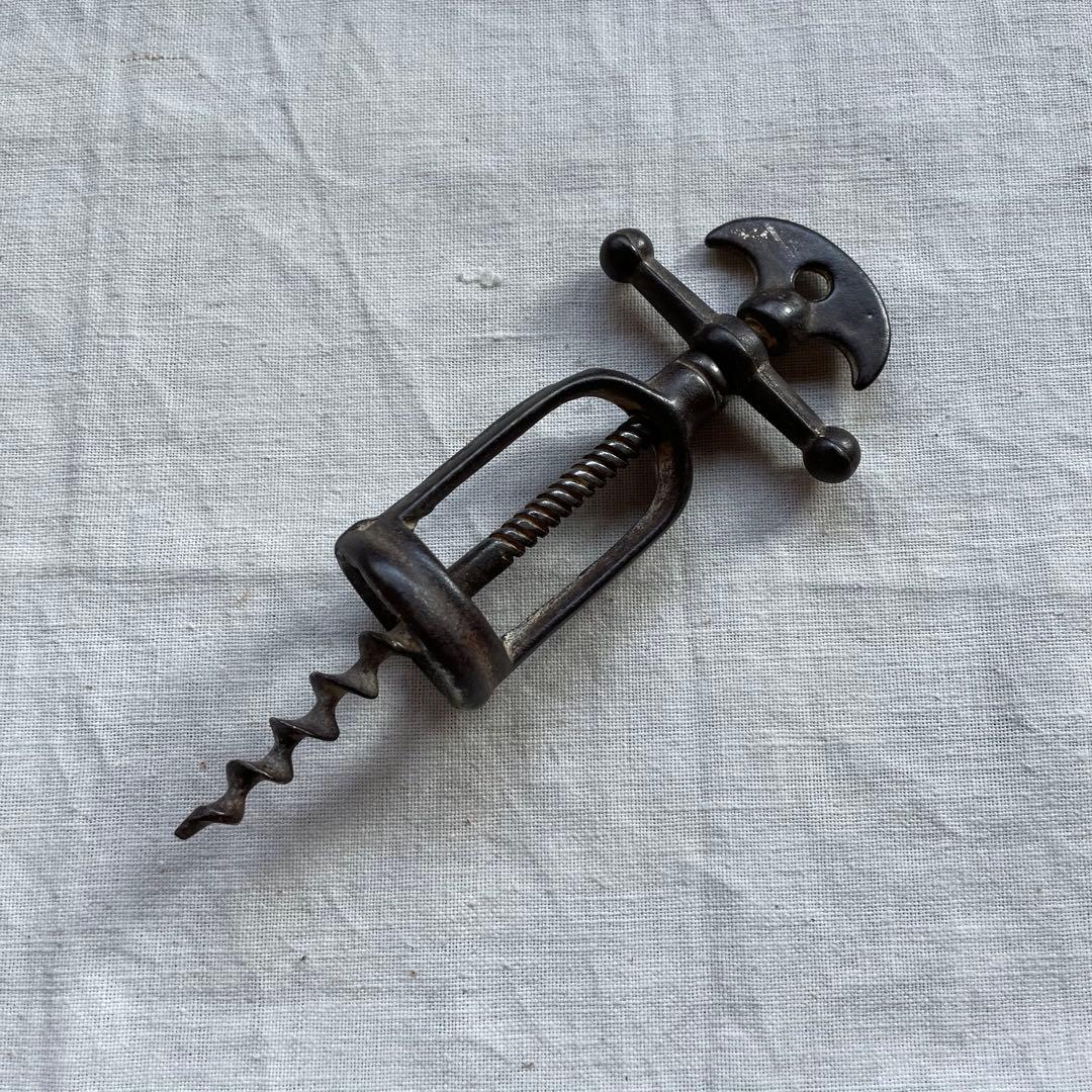 Antique French corkscrew (wine opener) shown on a light cloth background.
