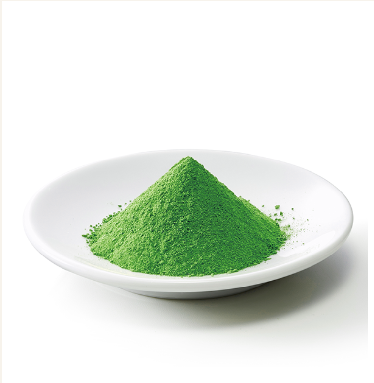 A white plate holding a small mound of bright green matcha powder (matcha green tea).