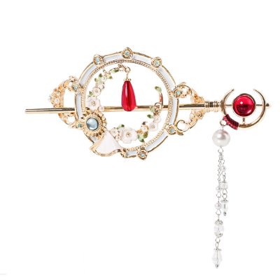Gold-tone decorative hair clip with circular filigree, a red center gem, and a dangling pearl-and-crystal chain.