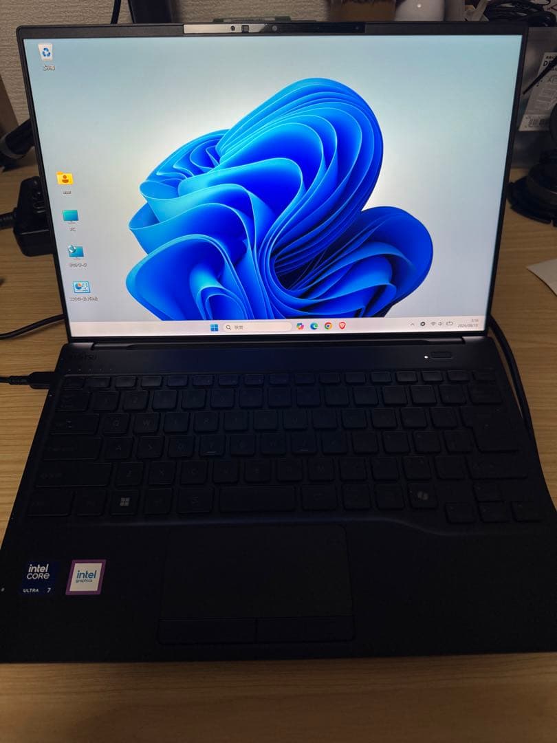 Open Fujitsu laptop on a wooden desk showing the screen with Windows desktop, keyboard, and Intel stickers.