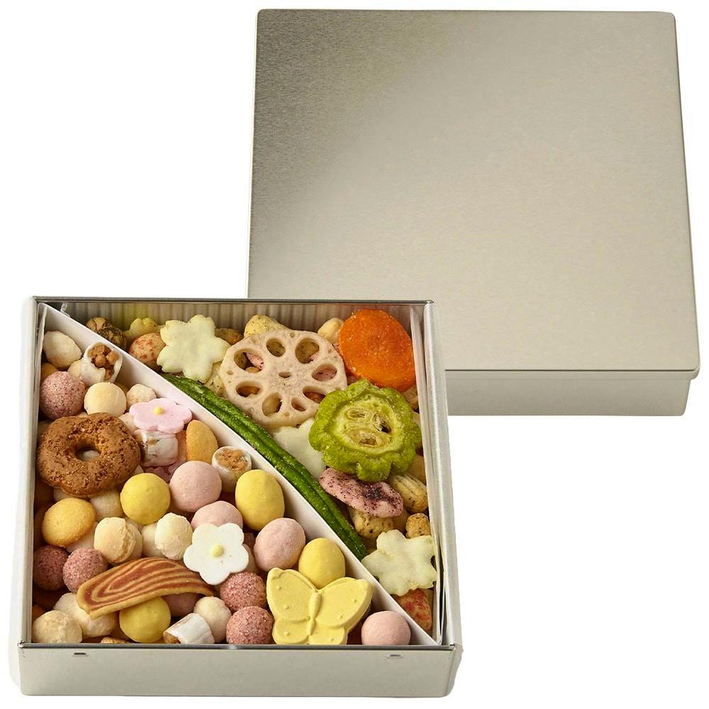 Open silver tin showing an assortment of cookies and rice crackers arranged inside with the lid placed behind.