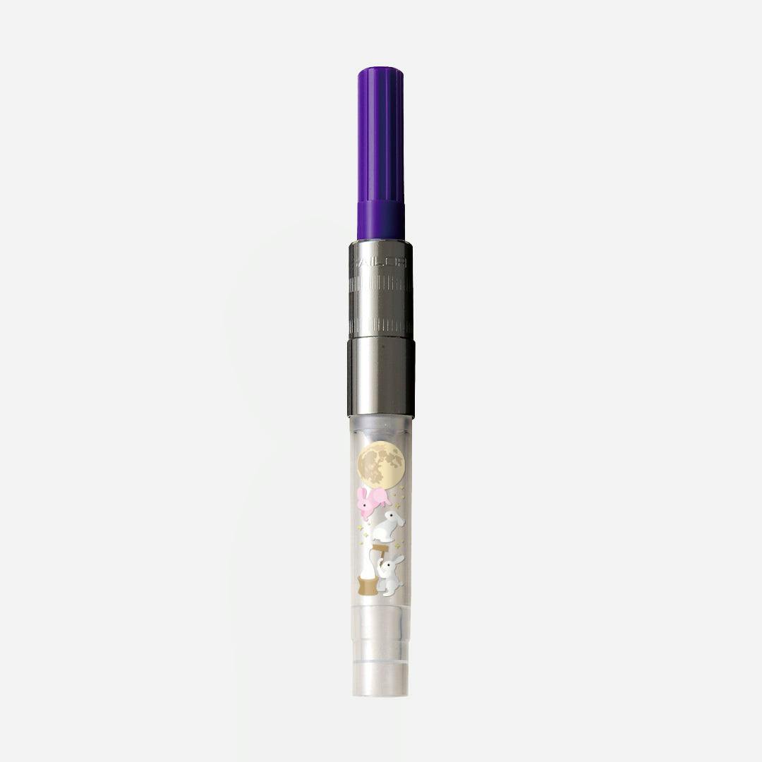 A fountain pen ink converter with a purple knob and a clear barrel decorated with a moon and rabbit illustrations.