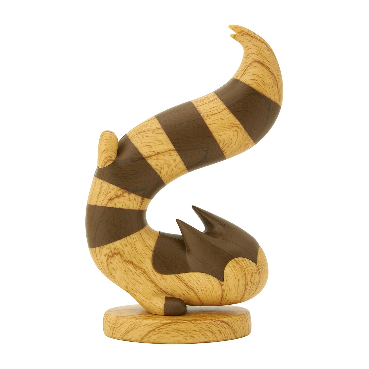Close-up of the wood-carved–style オオタチ (Furret) plastic figure showing its striped curled tail, body details, and round base.