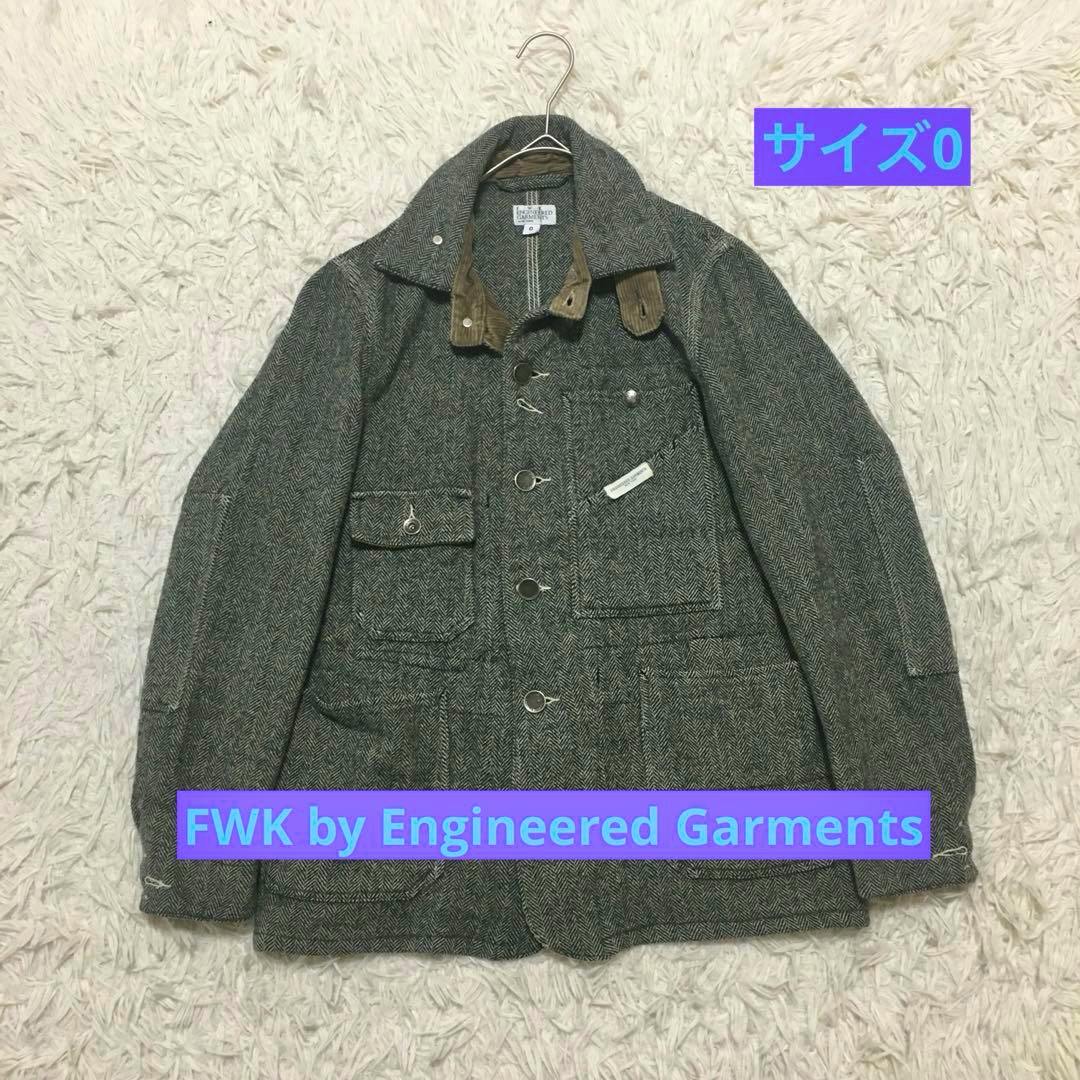 Gray wool herringbone men's coverall jacket laid flat on a rug on a hanger showing the front pockets and button closures.