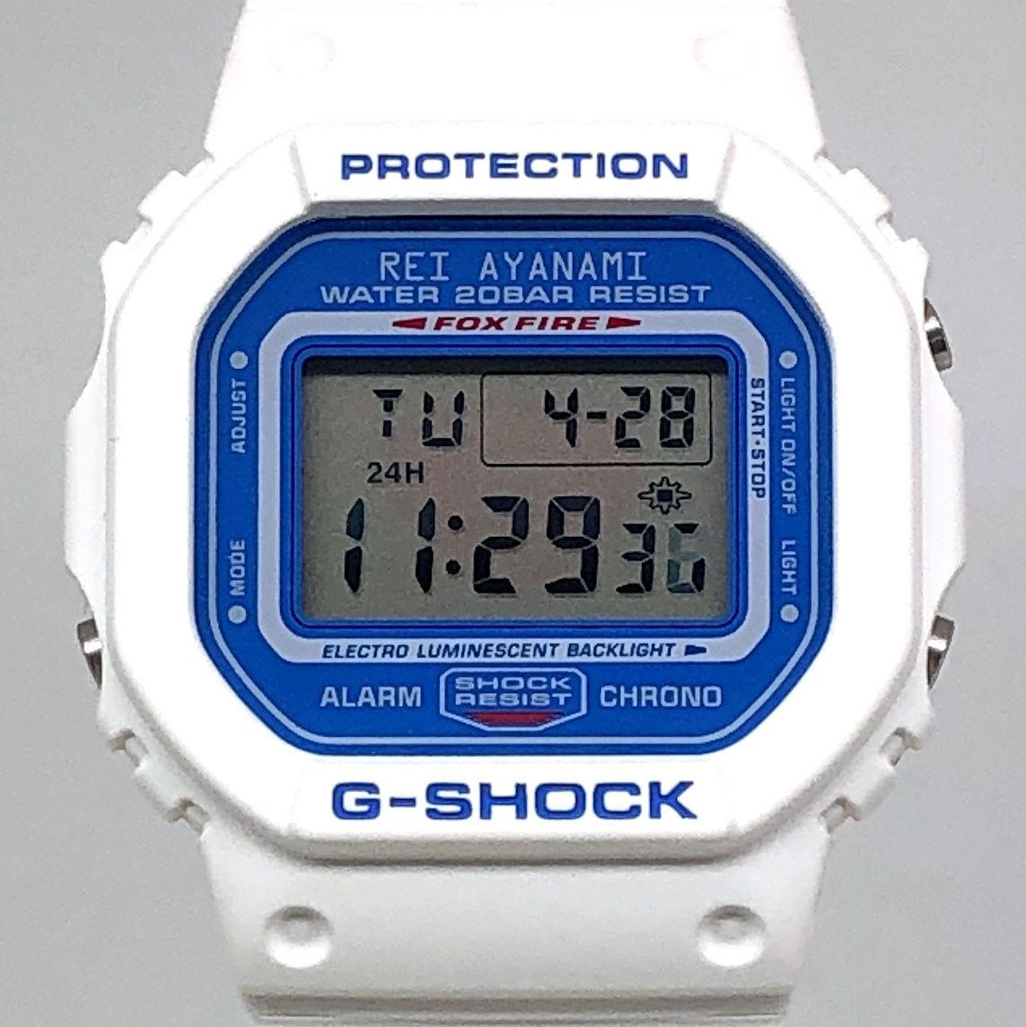 Close-up front view of a white G-SHOCK DW-5600VT watch showing the digital display and blue inner bezel with the text "REI AYANAMI".