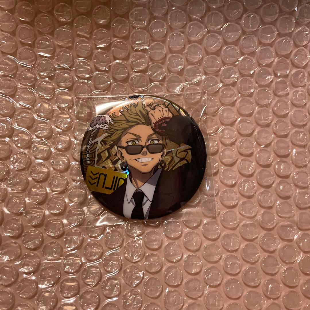A round can badge featuring an illustrated character in a black suit and sunglasses, sealed in plastic and shown on bubble wrap.