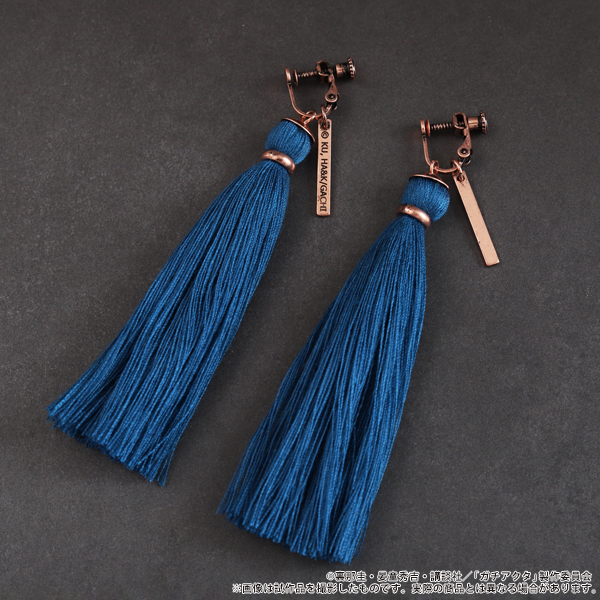 A pair of blue tassel earrings with copper-colored screw-back fittings and rectangular metal tags on a dark gray background.