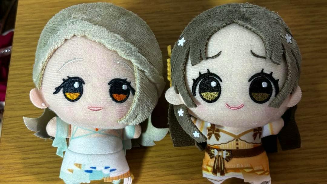 Front view of two chibi plush toys (学マス 篠澤広 and 倉本千奈) in stage outfits on a wooden surface.