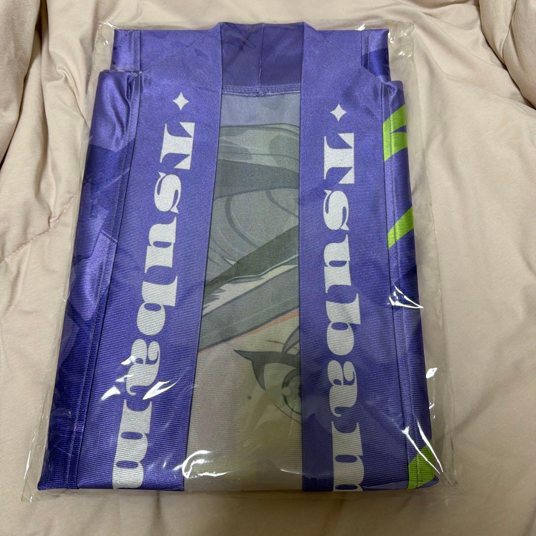 Folded purple happi coat with white "Tsubame" lettering, packaged in clear plastic on a beige surface.