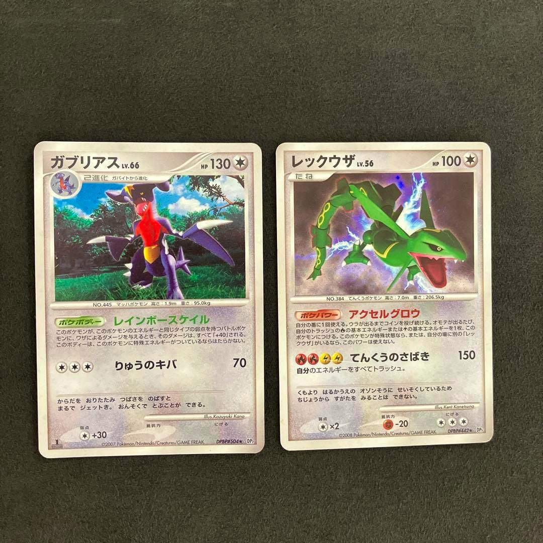 Fronts of two Japanese Pokémon trading cards showing ガブリアス (Garchomp) and レックウザ (Rayquaza) artwork on a dark background.