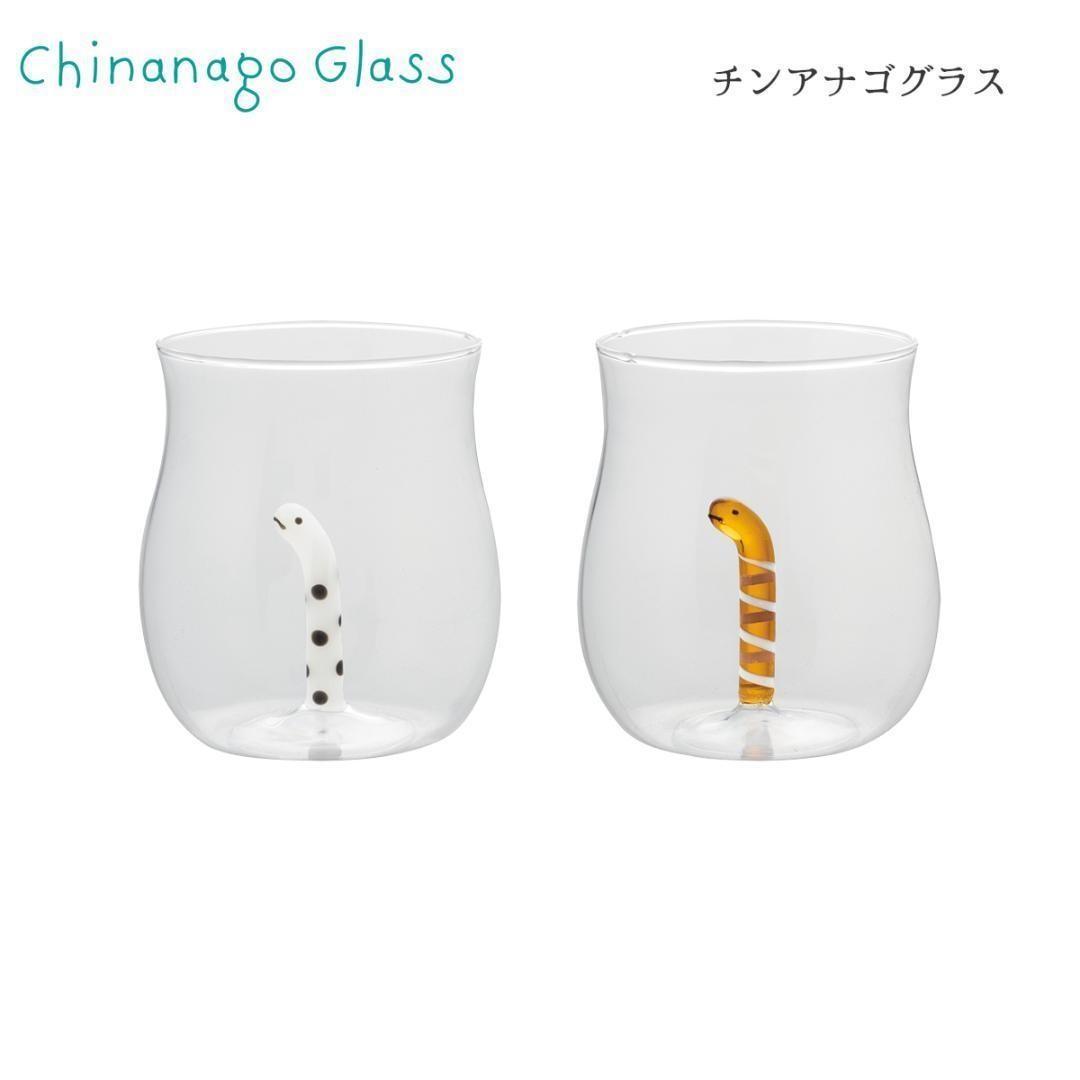 Two clear drinking glasses on a white background, each containing a small decorative eel-shaped glass figure inside.