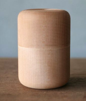 Wooden cylindrical tea canister photographed upright on a table.