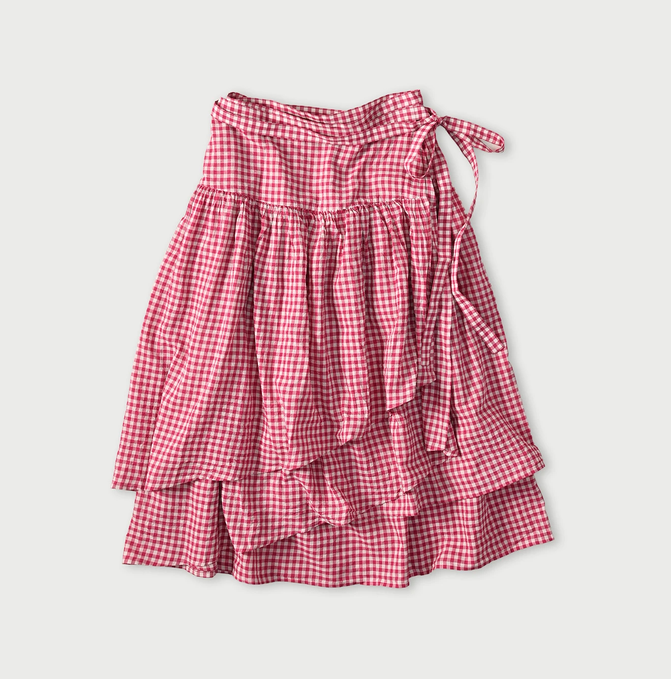 Red gingham gauze cotton women's skirt laid flat showing tiered ruffle layers and a waist tie.