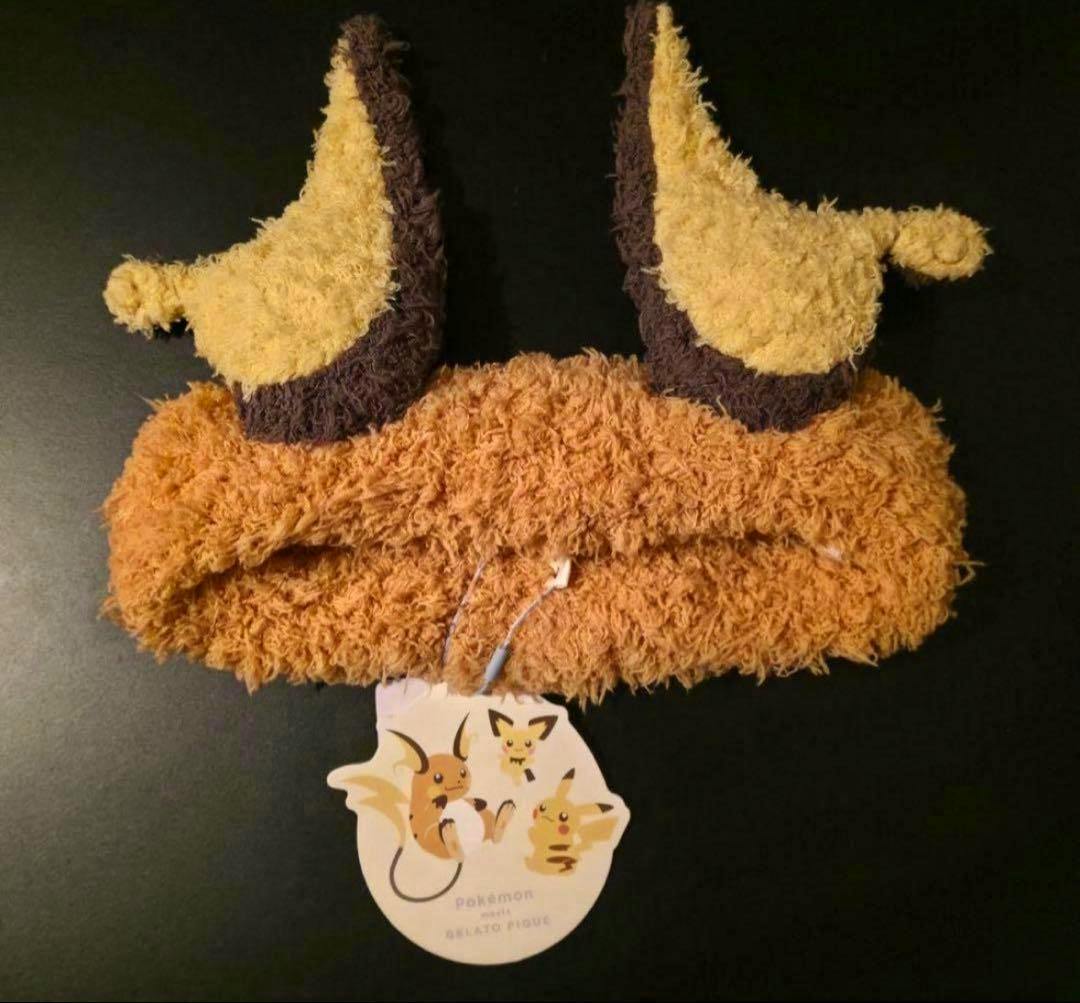 Fluffy GELATO PIQUE Raichu hairband with two ears and an attached Pokémon tag on a dark background.