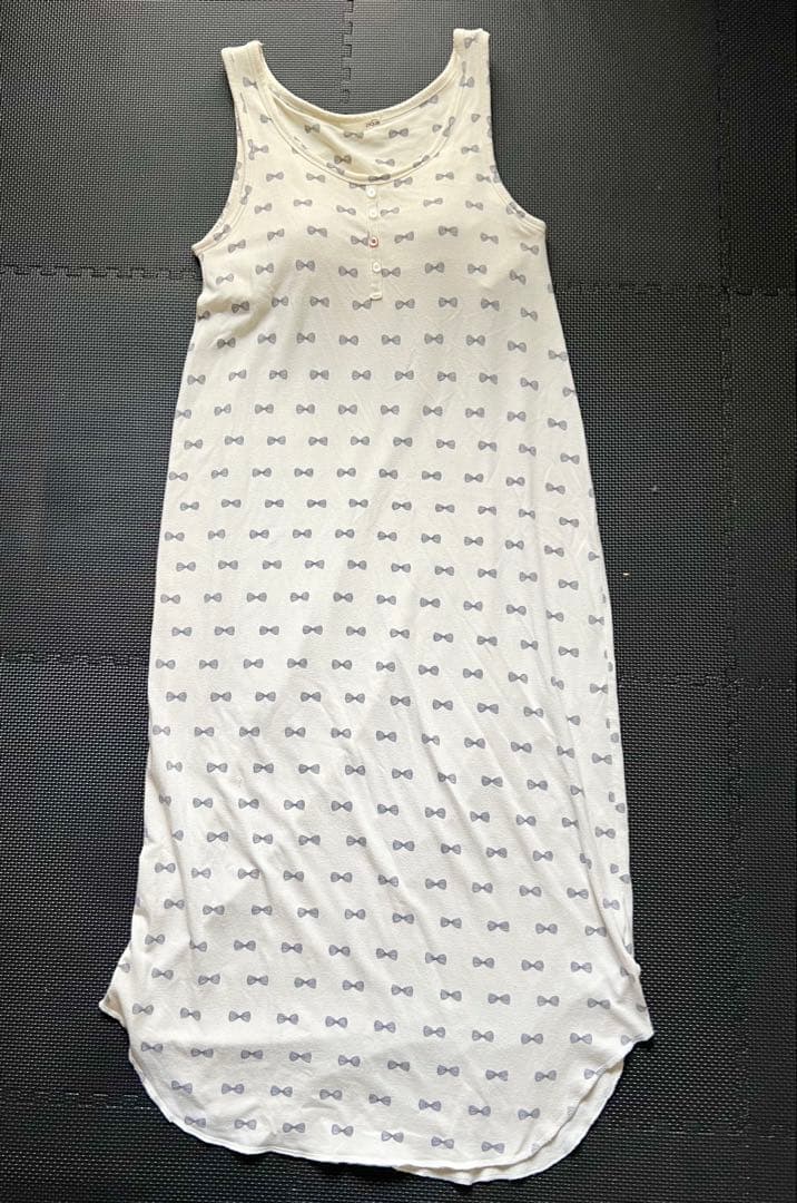 White padded long sleeveless loungewear dress with small ribbon (bow) pattern laid flat on a dark mat.