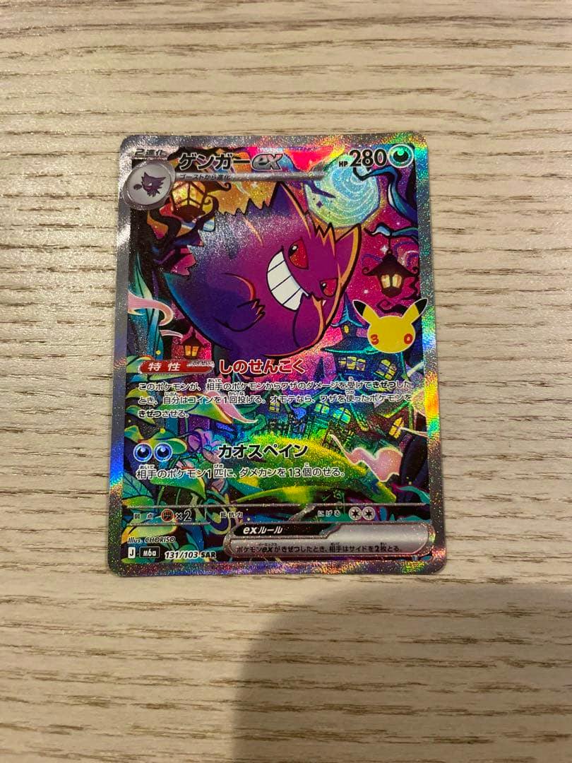 Front of a holographic Japanese trading card showing Gengar ex with Japanese text on a wood surface.