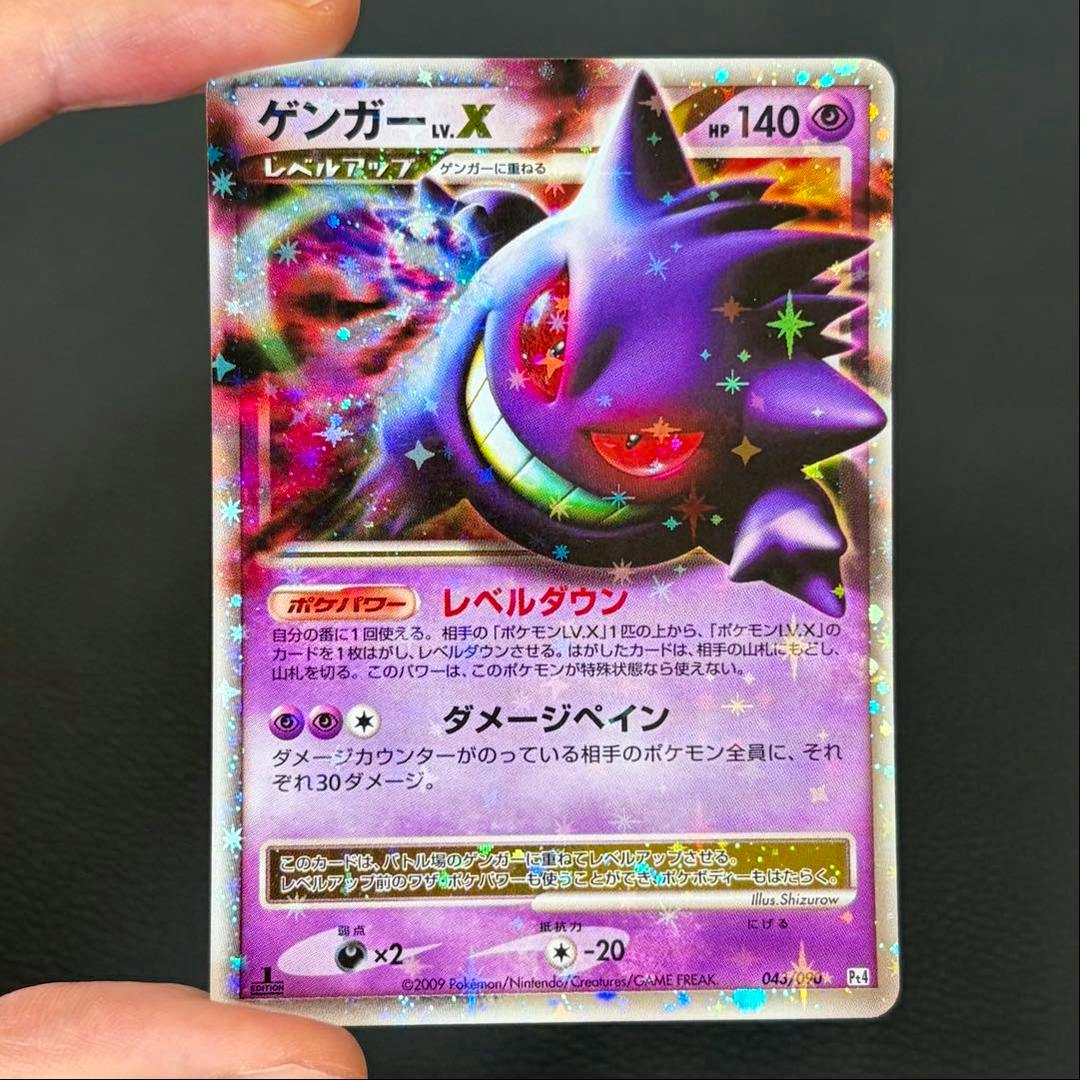 Front of a Gengar LV.X trading card with holographic star foil held by fingertips against a dark background.